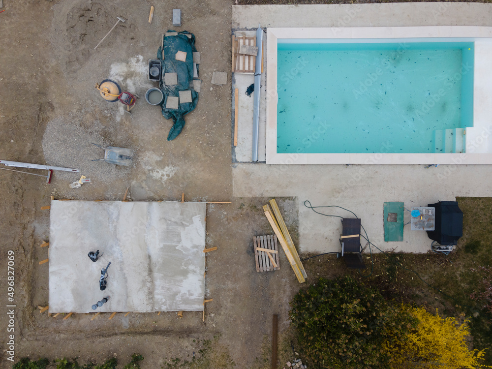Drone shot of pool construction site with concrete pad for heat pump and pool house in garden in austria