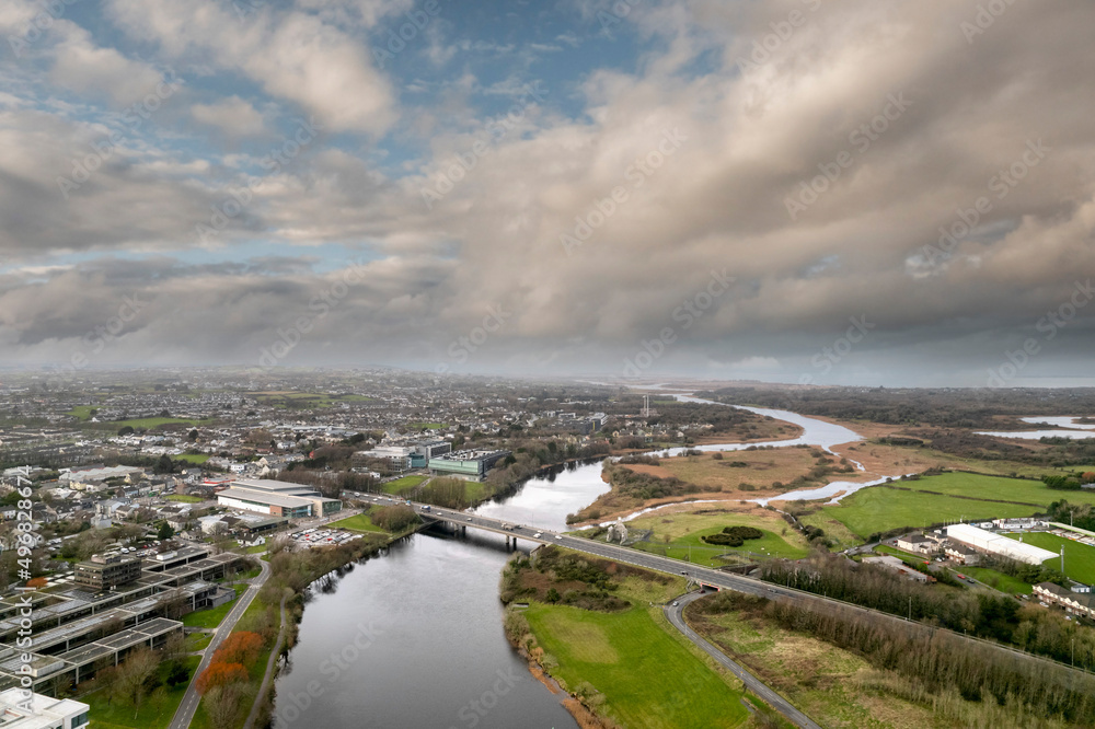 Aerial drone view on Galway city. River Corrib and NUI buildings. Calm dramatic sky. Bridge over a river and traffic.