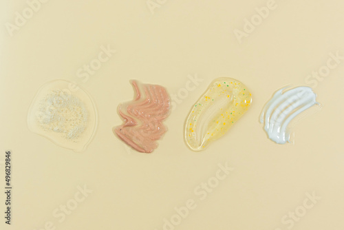 Textures of various cosmetics on a beige background. Spear of skincare cosmetics product, gel for washing, scrub, lotion or fluid, cream and serum for the face. Wellness and beauty concept