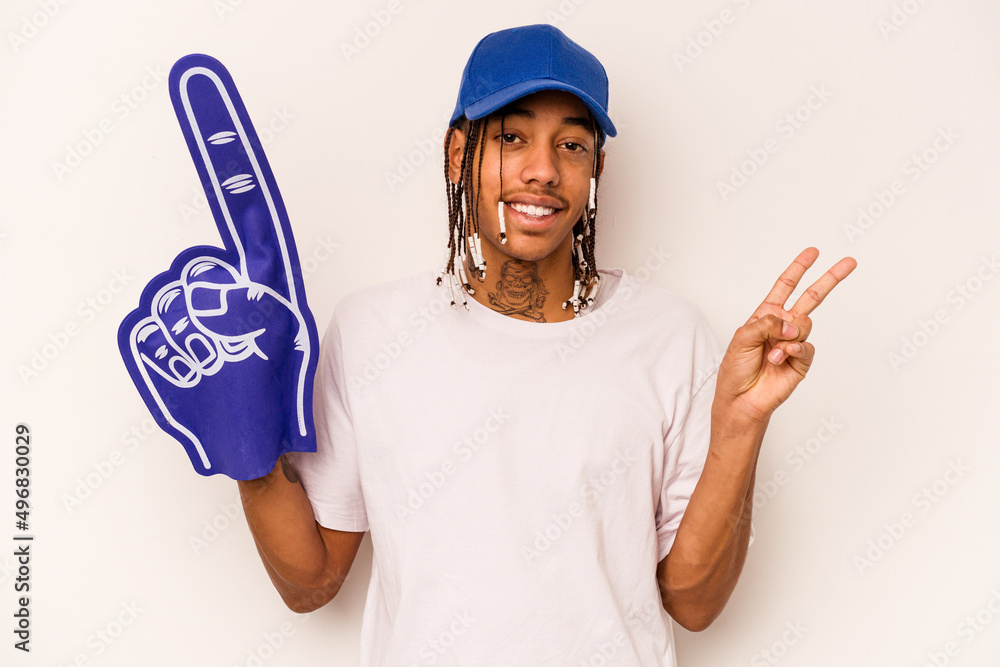 Young sports fan African American man isolated on white background joyful and carefree showing a peace symbol with fingers. Young sports fan African American man isolated on white background joyful and carefree showing a peace symbol with fingers.