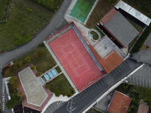 Aerial shot of a basketball playground with buildings and orchard photo