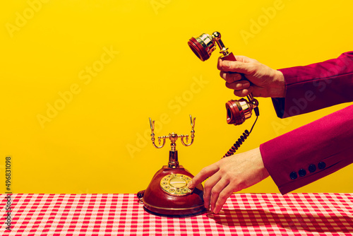 Retro objects, pop art photography. Female hand holding handset of vintage phone isolated on bright yellow background. Vintage, retro style