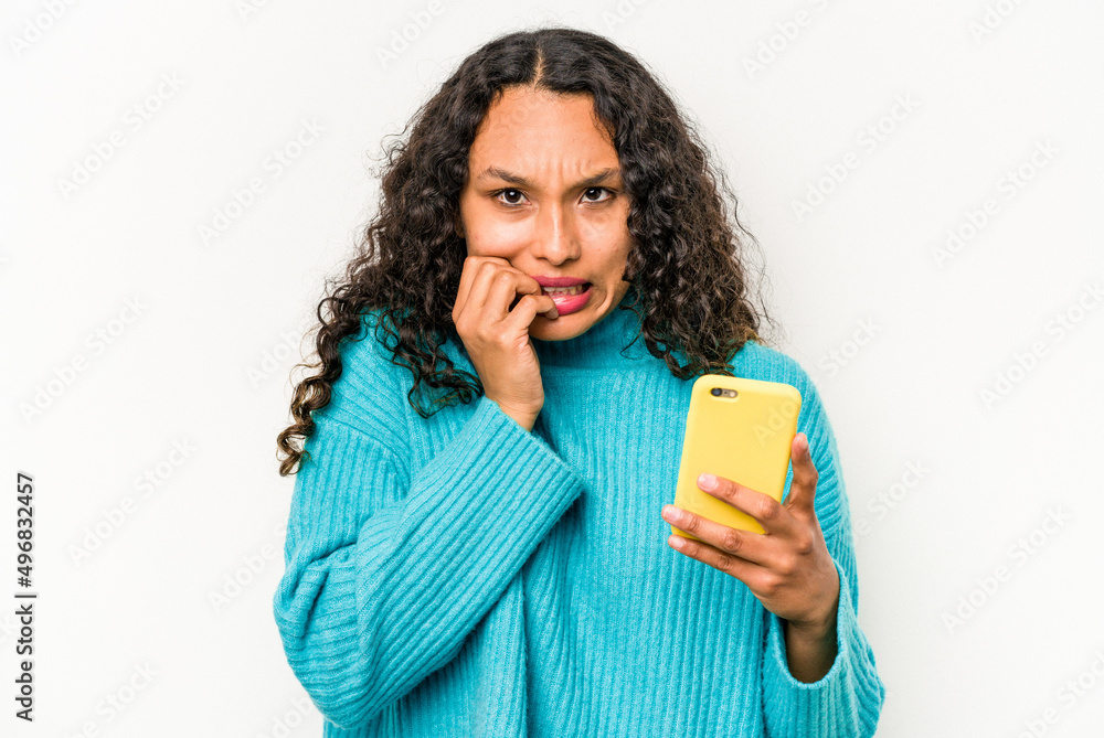 Young hispanic woman holding mobile phone isolated on white background biting fingernails, nervous and very anxious. Young hispanic woman holding mobile phone isolated on white background biting fingernails, nervous and very anxious.