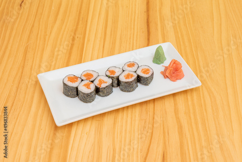 Norwegian salmon maki sushi with wasabi, nori seaweed, white rice and ginger on wooden table