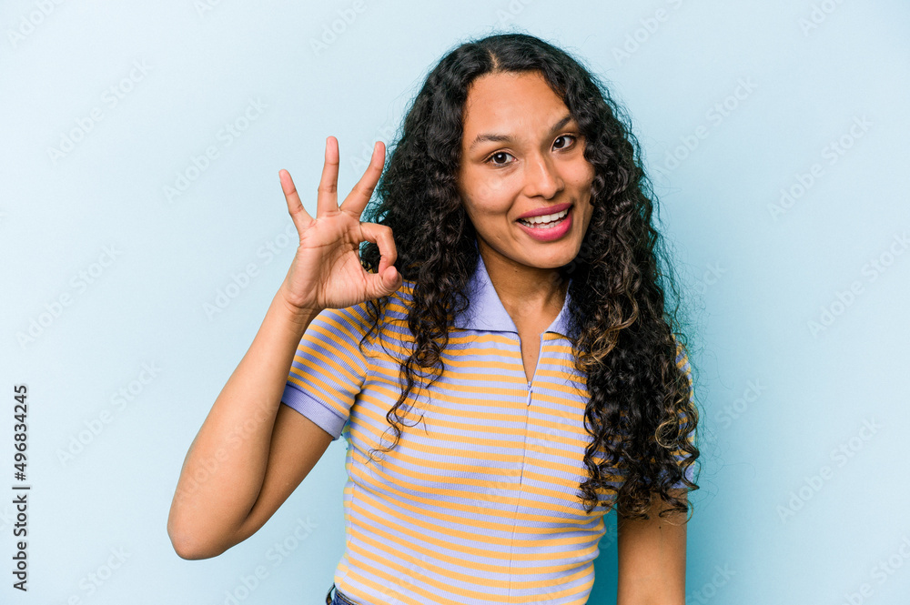 Young hispanic woman isolated on blue background cheerful and confident showing ok gesture. Young hispanic woman isolated on blue background cheerful and confident showing ok gesture.