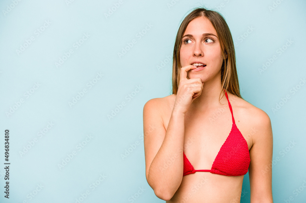 Fototapeta premium Young caucasian woman going to the beach isolated on blue background relaxed thinking about something looking at a copy space.