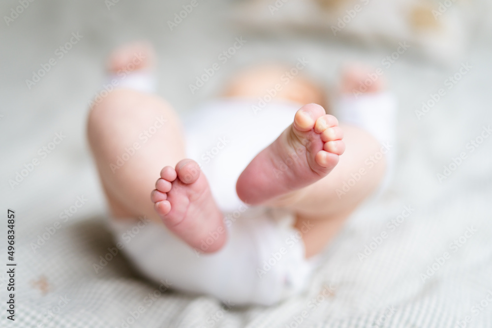 Baby tiny legs close up. Newborn wearing body lying on bed, first days at home after birth. baby care concept. Baby tiny legs close up. Newborn wearing body lying on bed, first days at home after birth. baby care concept.