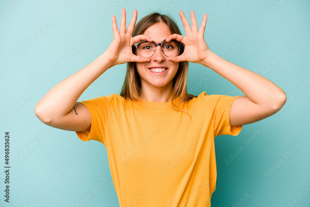 Young caucasian woman isolated on blue background showing okay sign over eyes Young caucasian woman isolated on blue background showing okay sign over eyes