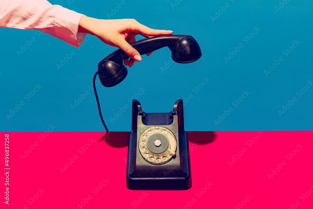 Retro objects, gadgets. Female hand holding handset of vintage phone isolated on blue and pink background. Vintage, retro fashion style. Pop art photography. - obrazy, fototapety, plakaty 