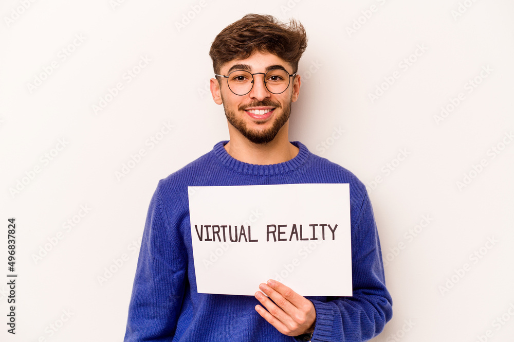 Young hispanic man holding a virtual reality placard isolated on white background happy, smiling and cheerful. Young hispanic man holding a virtual reality placard isolated on white background happy, smiling and cheerful.