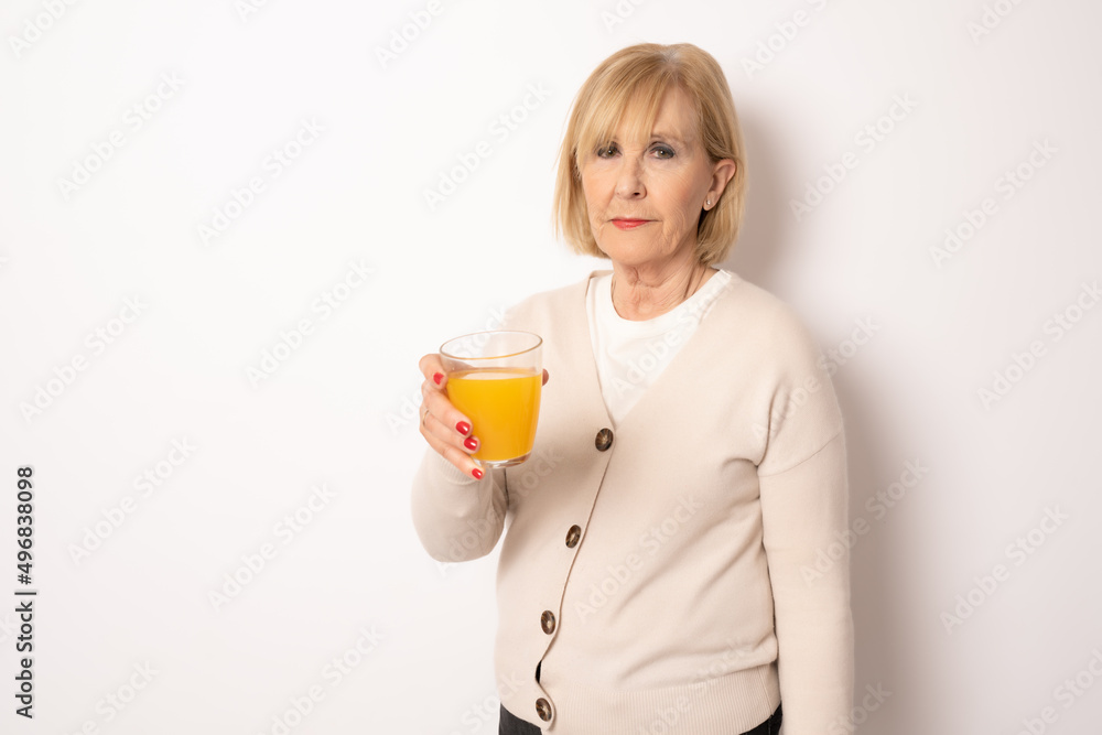 Portrait of senior woman holding orange juice glass Isolated over white Background Portrait of senior woman holding orange juice glass Isolated over white Background