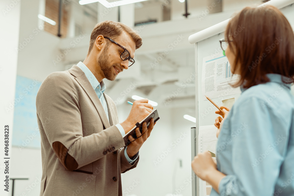 Obraz premium Man in eyeglasses writing notes in his notebook