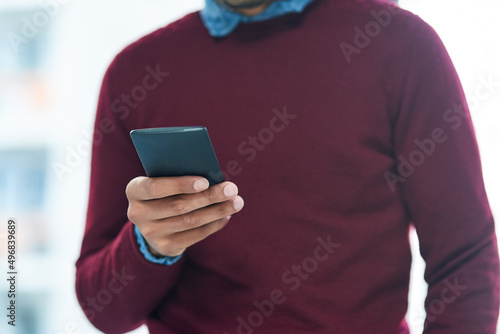 Just a text away from his clients. Shot of an unidentifiable businessman using his smartphone in the office.