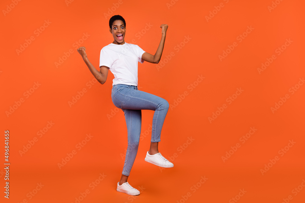 Full length photo of excited short hair androgyne lady fist up wear stylish t-shirt isolated bright color background Full length photo of excited short hair androgyne lady fist up wear stylish t-shirt isolated bright color background