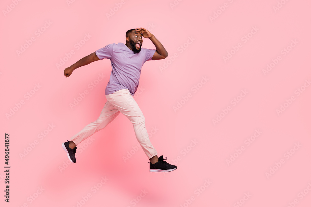 Full length body size view of attractive cheery guy jumping running looking far away isolated over pink pastel color background Full length body size view of attractive cheery guy jumping running looking far away isolated over pink pastel color background