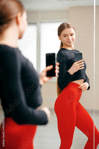 Fit woman in sportswear take photo selfie on phone in mirror