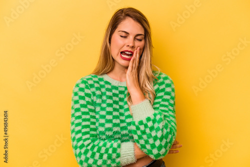 Young caucasian woman isolated on yellow background yawning showing a tired gesture covering mouth with hand.