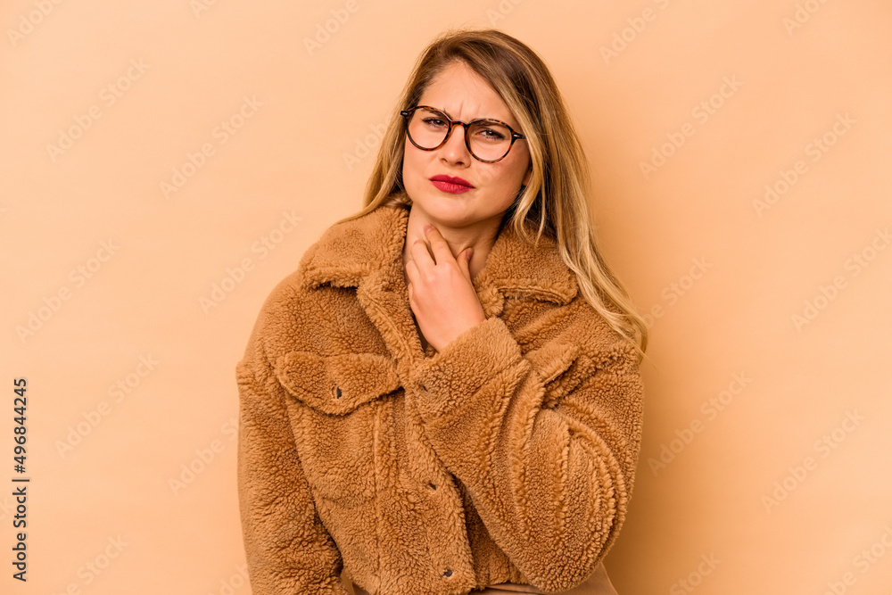 Young caucasian woman isolated on beige background suffers pain in throat due a virus or infection. Young caucasian woman isolated on beige background suffers pain in throat due a virus or infection.