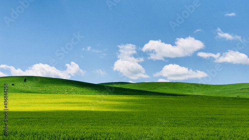 Scenic view of a landscape covered with green hills under a blue cloudy sky © Wirestock Creators