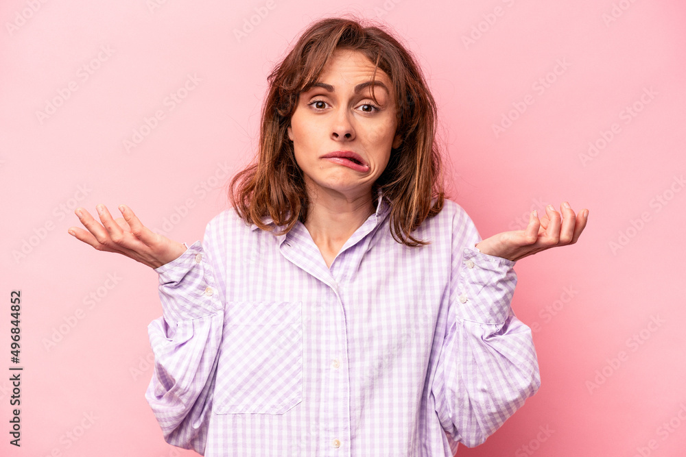 Young caucasian woman isolated on pink background doubting and shrugging shoulders in questioning gesture. Young caucasian woman isolated on pink background doubting and shrugging shoulders in questioning gesture.