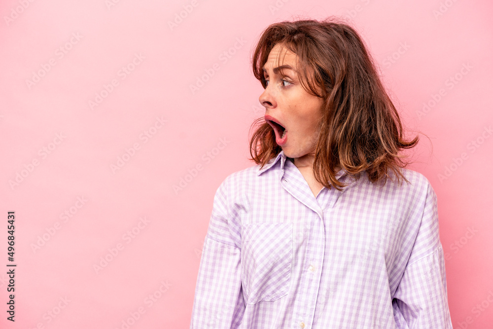 Young caucasian woman isolated on pink background being shocked because of something she has seen. Young caucasian woman isolated on pink background being shocked because of something she has seen.