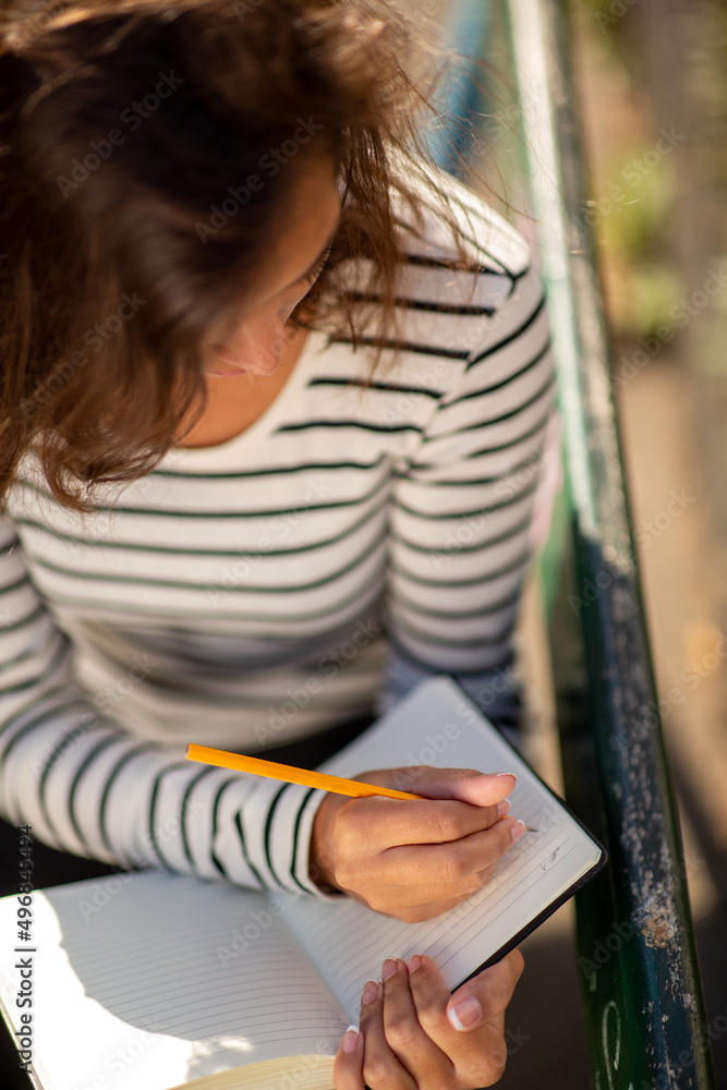 Top down young woman writing notes in diary Top down young woman writing notes in diary