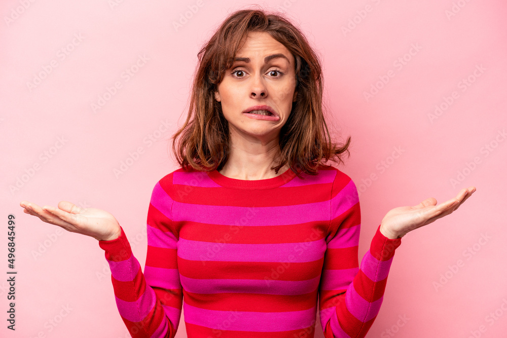 Young caucasian woman isolated on pink background confused and doubtful shrugging shoulders to hold a copy space. Young caucasian woman isolated on pink background confused and doubtful shrugging shoulders to hold a copy space.