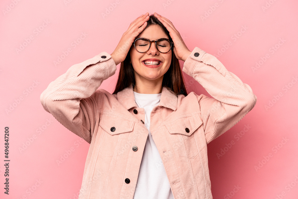 Young caucasian woman isolated on pink background laughs joyfully keeping hands on head. Happiness concept. Young caucasian woman isolated on pink background laughs joyfully keeping hands on head. Happiness concept.