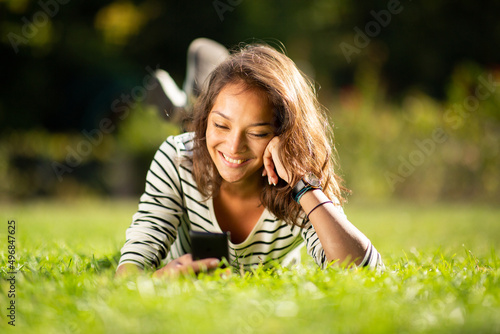 attractive young woman relaxing in park with mobile phone