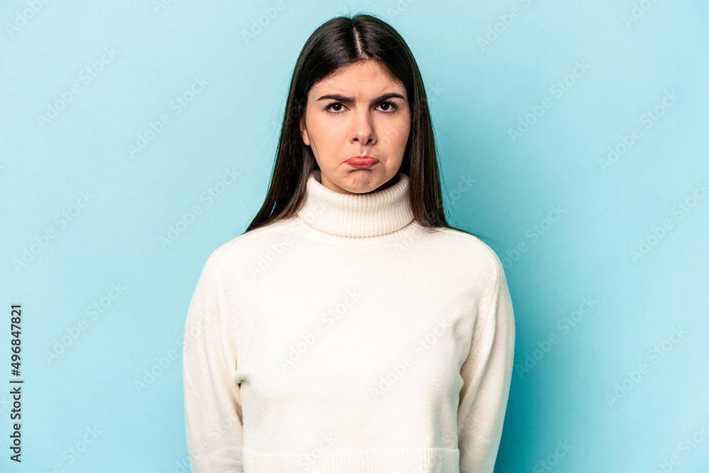 Fototapeta premium Young caucasian woman isolated on blue background sad, serious face, feeling miserable and displeased.