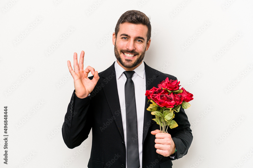 Young caucasian man holding a bouquet of flowers isolated on white background cheerful and confident showing ok gesture. Young caucasian man holding a bouquet of flowers isolated on white background cheerful and confident showing ok gesture.
