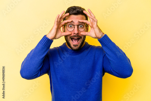 Young caucasian man isolated on yellow background keeping eyes opened to find a success opportunity.