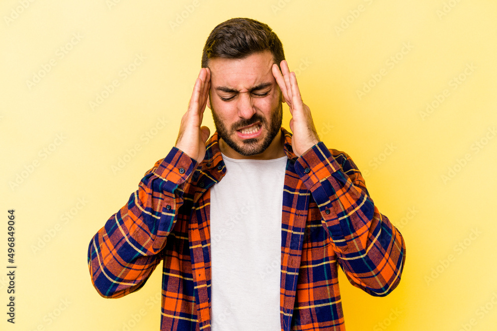 Young caucasian man isolated on yellow background touching temples and having headache. Young caucasian man isolated on yellow background touching temples and having headache.