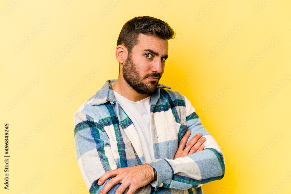Young caucasian man isolated on yellow background suspicious, uncertain, examining you. Young caucasian man isolated on yellow background suspicious, uncertain, examining you.