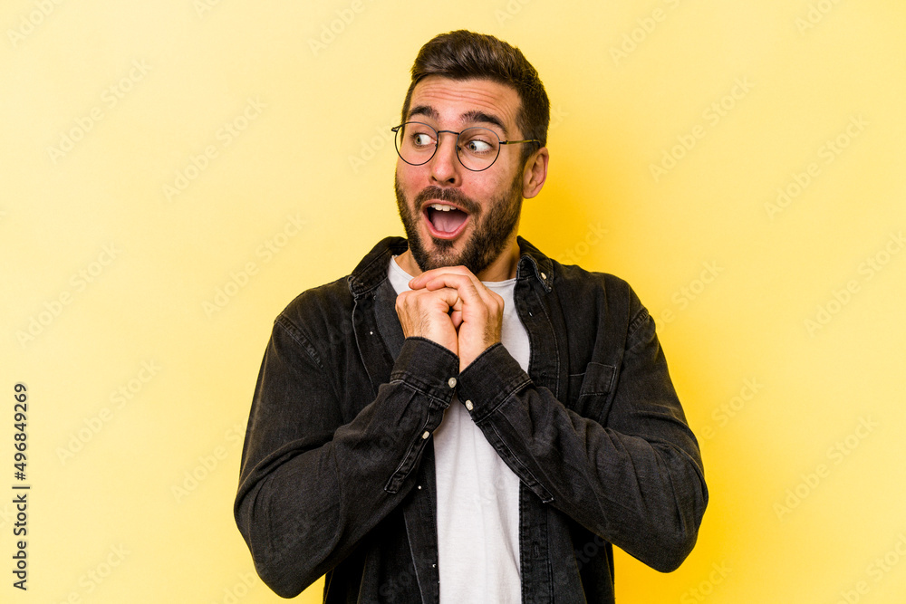 Young caucasian man isolated on yellow background praying for luck, amazed and opening mouth looking to front. Young caucasian man isolated on yellow background praying for luck, amazed and opening mouth looking to front.