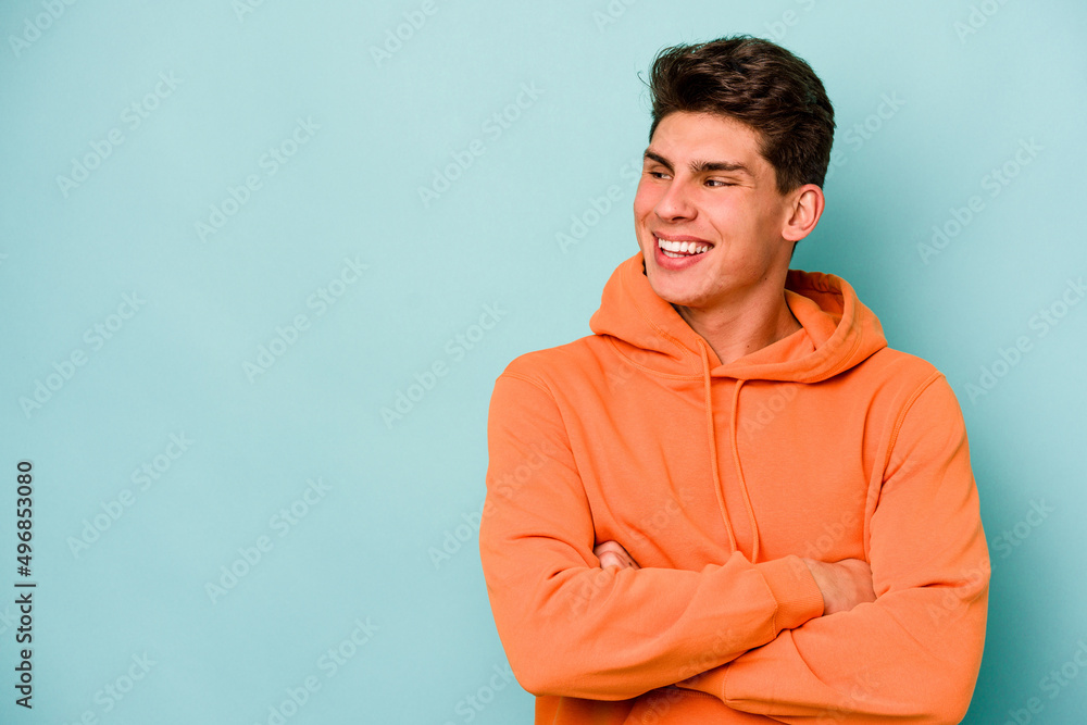 Young caucasian man isolated on blue background smiling confident with crossed arms. Young caucasian man isolated on blue background smiling confident with crossed arms.