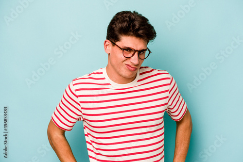 Young caucasian man isolated on blue background confused, feels doubtful and unsure.