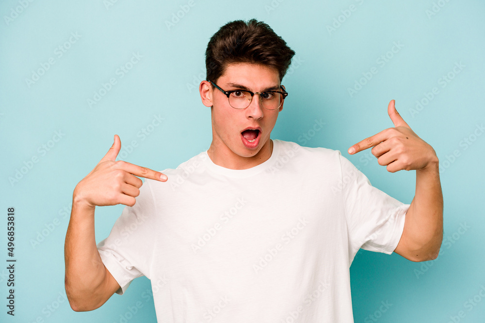 Young caucasian man isolated on blue background points down with fingers, positive feeling. Young caucasian man isolated on blue background points down with fingers, positive feeling.