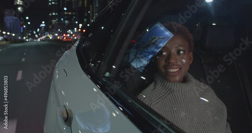 Happy Black Woman in Taxi backseat during night ride in the city