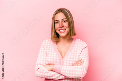 Young caucasian woman isolated on pink background who feels confident, crossing arms with determination.