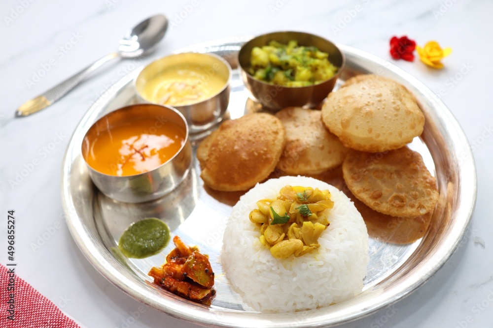 Indian vegetarian Thali or platter includes Aloo ki sabji, dal rice, Puri bhaji, Shrikhand or Srikhand, Aamras, papad, pickle, and chutney. Mashed potato curry or masala. Indian Festival food Thali.