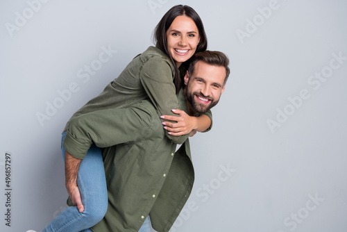 Portrait of attractive cheerful amorous couple married spouses piggy backing isolated over grey pastel color background