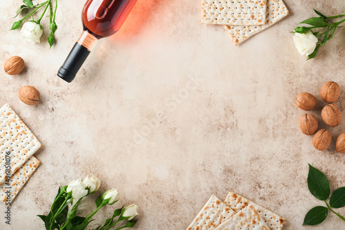 Passover celebration concept. Matzah, red kosher walnut and spring beautiful rose flowers.. Traditional ritual Jewish bread on sand color old concrete background. Passover food. Pesach Jewish holiday. photo