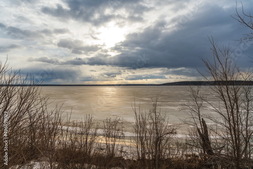Sunlight breaking through spring clouds over a frozen Lake Dore in back country Ontario..