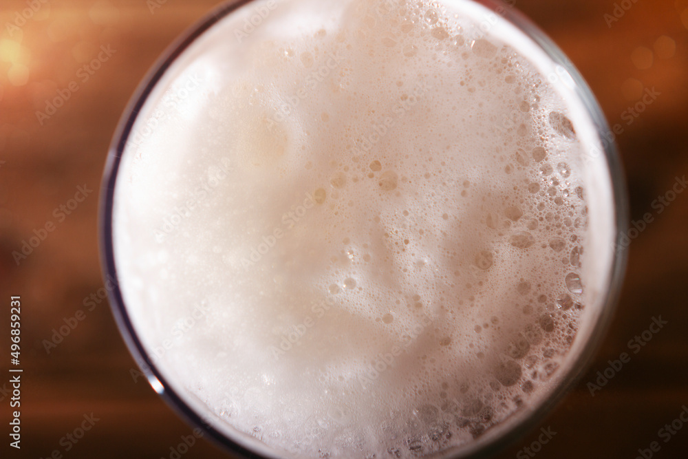 Beer foam in a glass mug close-up, top view drink. Beer on a wooden table in a pub or bar Beer foam in a glass mug close-up, top view drink. Beer on a wooden table in a pub or bar