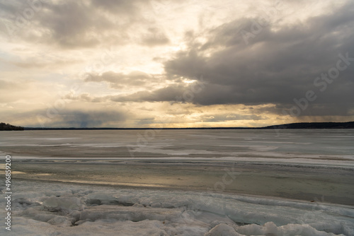 Sunlight breaking through spring clouds over a frozen Lake Dore in back country Ontario.. 