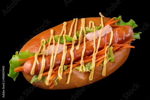 delicious hot dog with sausage lettuce carrots and sauce on a black background