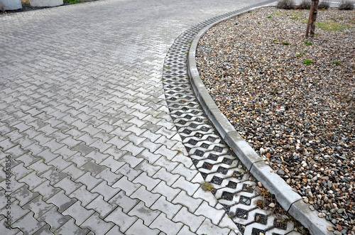 newly established street in the city, the longitudinal car park is made of perforated concrete infiltration tiles on the side of the road at the curb. slope stabilization using a terraced palisade