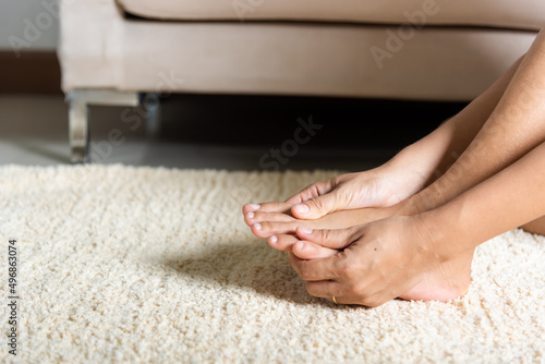 Foot pain, Asian woman holds her toe injury feeling pain her foot at home, female suffering from feet ache use hand massage relax muscle from toe in house interior, Healthcare problems medical concept © sorapop