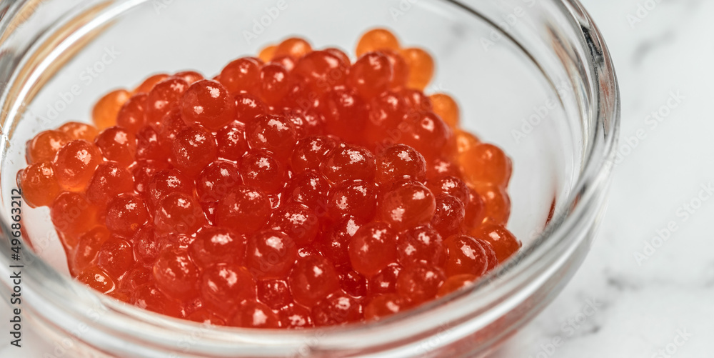 Salmon Red Caviar. Red fish caviar on a spoon in glass bowl. Raw seafood. Luxury delicacy food. appetizer, selective focus, place for text Salmon Red Caviar. Red fish caviar on a spoon in glass bowl. Raw seafood. Luxury delicacy food. appetizer, selective focus, place for text